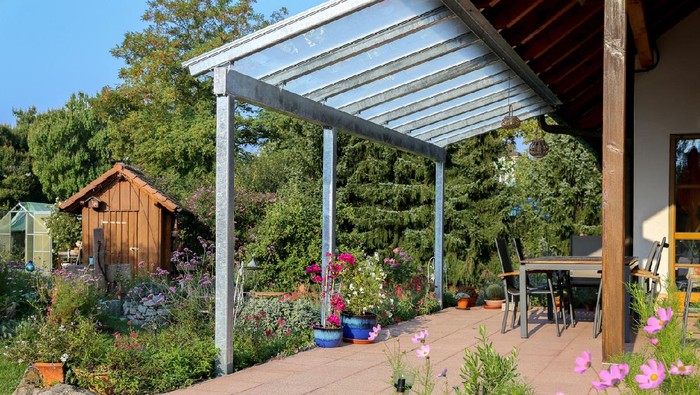 ilustrasi kanopi rumah minimalis Glass patio cover with a view of the garden.