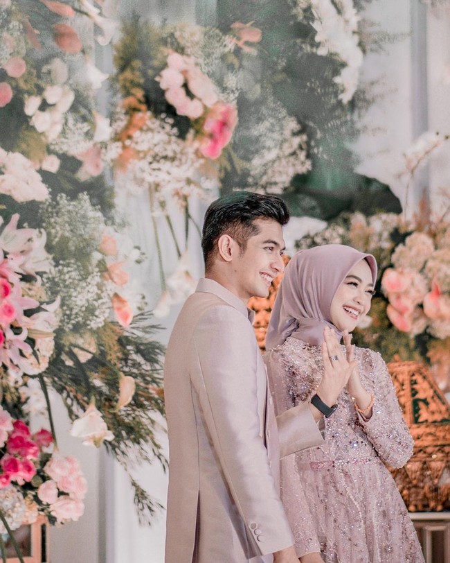 Keduanya pun tampak serasi dengan busana bernuansa pink blush. Terlihat modern dan romantis, Ria dan Ryan tetap menambahkan sentuhan tradisional Aceh dalam pakaian mereka. Foto: Instagram @riaricis1795