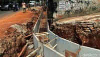 Seorang warga melintasi di samping area perbaikan drainase atau saluran air di Jalan Inspeksi Kalimalang, Jakarta, Jumat (24/9/2021).
