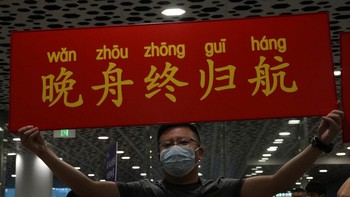 Seorang pria membentangkan poster bertuliskan Meng Wanzhou akhirnya kembali. Foto: AP