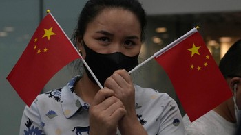 Seorang perempuan mengibarkan bendera China. Dia termasuk salah satu dari sekian banyak orang yang menyambut kepulangan Meng di bandara Baoan International Airport di kota Shenzhen. Foto: AP