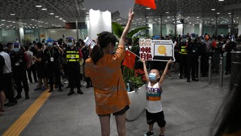 Seorang anak kecil membawa poster dengan ilustrasi tablet Huawei sementara ibunya mengibarkan bendera China. Foto: AP
