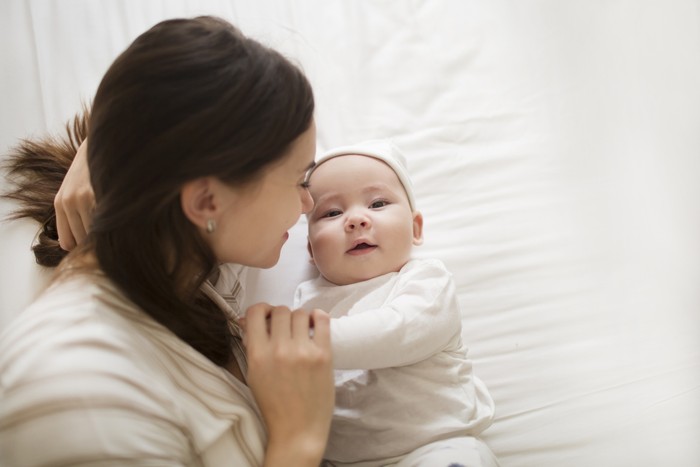 1179937689 Happy mother and baby child lying on bed together