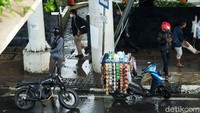 Ada yang berteduh dan menggunakan jas hujan.
