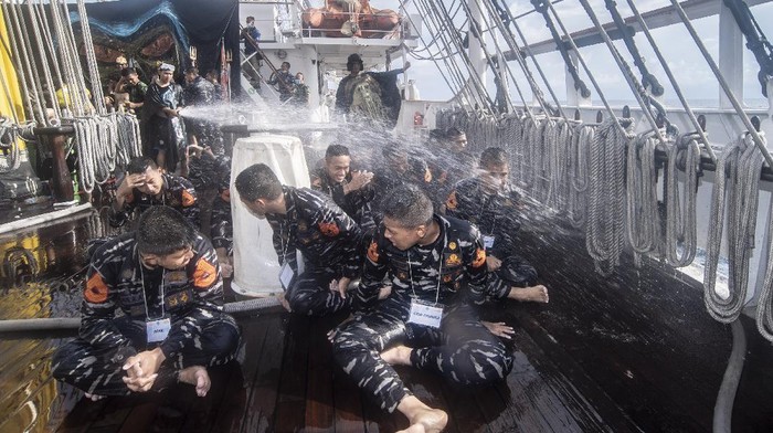 Perwira Pelaksana (Palaksa) KRI Bima Suci Mayor Laut (P) Sugeng Hariyanto (kanan) membersihkan rambut Taruna Akademi Angkatan Laut (AAL) Tingkat III Angkatan ke-68 saat mengikuti prosesi Mandi Khatulistiwa di geladak KRI Bima Suci di perairan Indonesia, Jumat (24/9/2021). Prosesi Mandi Khatulistiwa merupakan tradisi pelaut dunia saat melintasi garis khatulistiwa. ANTARA FOTO/Muhammad Adimaja/hp.