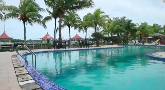 Adapun kolam renang langsung berhadapan dengan sebuah danau. Deretan pohon kelapa yang tumbuh di pinggir kolam semakin memperindah suasana. (Foto: YouTube/Catatan si Andre)