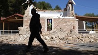 Seorang warga melintas di depan Kapel Ortodok yang hancur diguncang gempa di Desa Arcalochori, Pulau Kreta, Yunani.