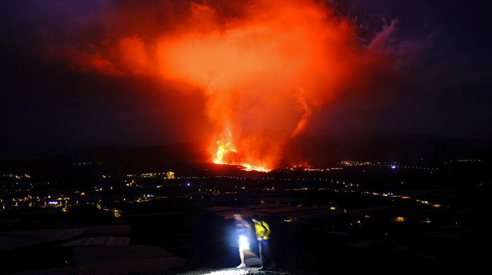 In this photo made available by Ume (Unidad Militar de Emergencias), Military Emergency Unit personal take gas reading measurements near a volcano on the Canary island of La Palma, Spain, in the early hours of Tuesday Sept. 28, 2021. Lava flowing from an erupting volcano on the Spanish island of La Palma has picked up pace on its way to the sea. Officials say it is now within about 800 meters (875 yards) of the shoreline. When the molten rock eventually meets the sea water it could trigger explosions and toxic gas. (Luismi Ortiz/UME via AP)