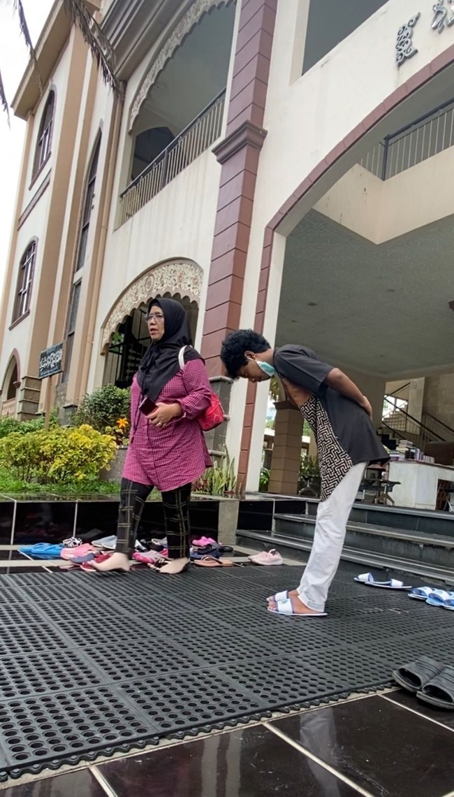 Ia menuturkan jika biasanya ia melihat seorang bapak-bapak yang merapikan sandal para jamaah yang ingin salat. Namun ternyata sekarang dijaga oleh anak remaja dengan nada yang khas saat menyapa jamaah. Mat Peci pun langsung menyapa remaja tersebut. Halo selamat datang, tempat wudhu sebelah sini, toilet sebelah sana dan sandal silahkan disini. Pokoknya seperti yang ada di video, habis salat aku duduk dan iseng aja melihat dia berbeda dan menarik, jelasnya. Foto: Dok. pribadi Mat Peci.