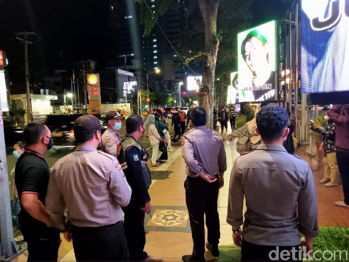 Banyak penggemar Boyband NCT, yang foto-foto dengan background videotron di depan Plaza Surabaya. Mereka diingatkan untuk tetap prokes.
