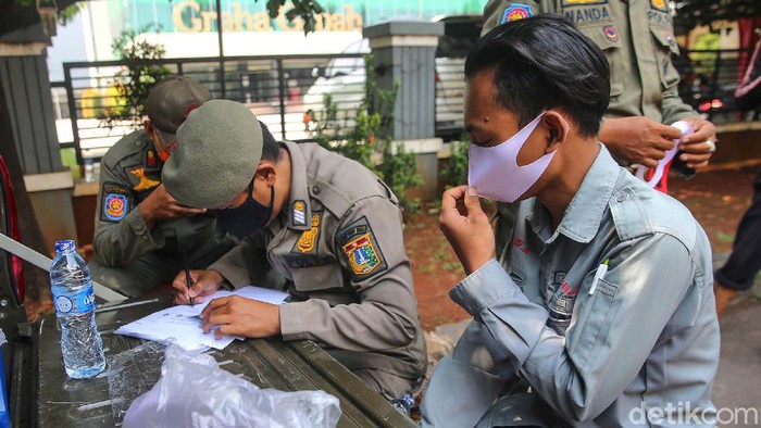 Saptol PP gelar razia masker di Jalan Raya Pasar Minggu, Jakarta. Sebanyak 15 pengendara diberhentikan dan mendapatkan sanksi ringan karena tidak memakai masker.