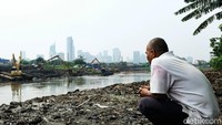 Seorang warga menyaksikan pengerukan lumpur di wilayah Tanah Abang, Jakarta Pusat.