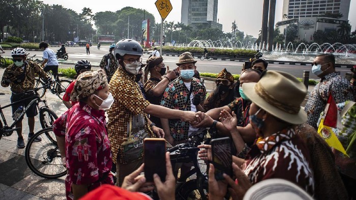 ANIES BERSEPEDA PERINGATI HARI BATIK NASIONAL Gubernur DKI Jakarta Anies Baswedan (kiri) mengenakan baju batik saat menyapa para pesepeda di kawasan Bundaran HI, Jakarta, Sabtu (2/10/2021). Kegiatan berbaju batik saat bersepeda itu sebagai bentuk perayaan memperingati Hari Batik Nasional setiap tanggal 2 Oktober. ANTARA FOTO/Aprillio Akbar/pras.