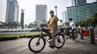 Dengan mengenakan batik, Anies bersepeda di kawasan Bundaran Hotel Indonesia (HI), Jakarta.