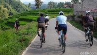 Petani melihat para pesepeda melintasi pesawahan. Kawasan ini berada pada ketinggian sekitar 1.000 mdpl.