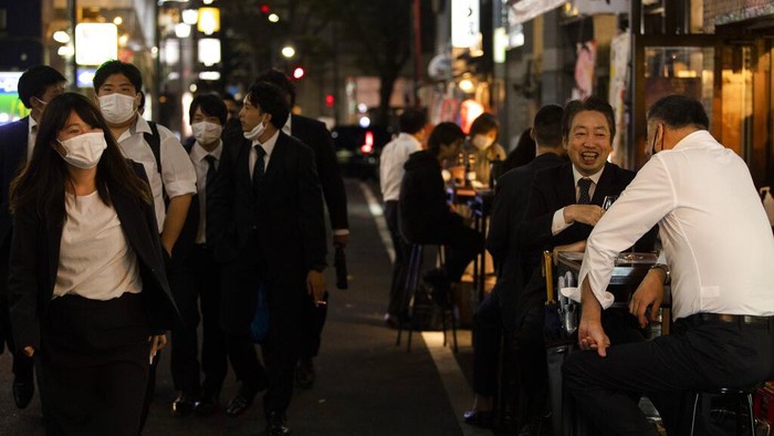 People hang out on a street as others eat and drink at restaurants and bars in Tokyo on the first night of the governments lifting of a coronavirus state of emergency Friday, Oct. 1, 2021. (AP Photo/Hiro Komae)