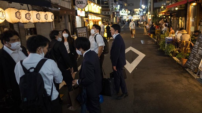 People hang out on a street as others eat and drink at restaurants and bars in Tokyo on the first night of the government's lifting of a coronavirus state of emergency Friday, Oct. 1, 2021. (AP Photo/Hiro Komae)