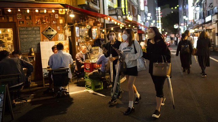 Darurat COVID-19 Dicabut, Warga Jepang Asik Nongkrong Lagi People hang out on a street as others eat and drink at restaurants and bars in Tokyo on the first night of the government's lifting of a coronavirus state of emergency Friday, Oct. 1, 2021. (AP Photo/Hiro Komae)