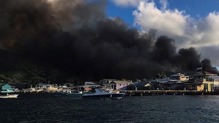 View of a fire in Guanaja island, in the tourist Islas de la Bahia, Honduras, on October 2, 2021. - A huge fire advanced consuming dozens of homes on the paradisiacal Honduran island of Guanaja, amid the desperation of firefighters and neighbors to control the flames, while evacuating hundreds of people, including at least four with burns, authorities reported. (Photo by anuar acosta / AFP)