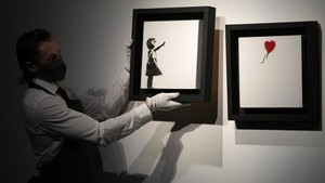 Nah, kalau foto yang satu ini adalah Banksy Girl and the Balloon yang dilelang Sothebys senilai Rp 67 miliar. Wah!  Foto: AP/Alastair Grant