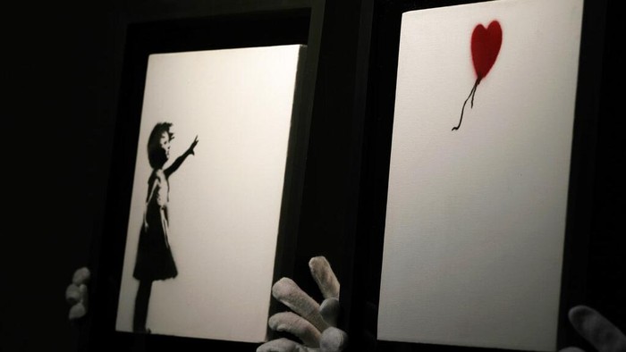 Wow! Karya Members of staff hold up an artwork by British graffiti artist Banksy entitled 'Girl and Ballon' (two parts), during a pre-auction press viewing at Christie's auction house in London, Friday, Oct. 1, 2021. The diptych is expected to sell for 2,500,000 million pounds sterling (US, $3.5-4.8 million, euros 3-4.1 million). (AP Photo/Alastair Grant)