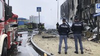 Bangunan tempat pesawat jatuh rusak parah akibat kebakaran yang terjadi, sementara beberapa mobil yang diparkir di sekitarnya juga terbakar.