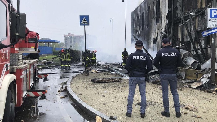 Pesawat Ringan Tabrak Gedung di Italia, 8 Orang Tewas Italian police stand by as firefighters work at the site of a plane crash, in San Donato Milanese suburb of Milan, Italy, Sunday, Oct. 3, 2021. According to media reports, a small plane carrying five passengers and the pilot crashed into an apparently vacant office building in a Milan suburb. Their fates were not immediately known. (Italian Police via AP)
