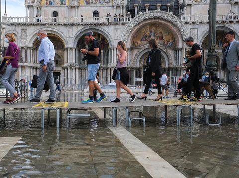 People walk on a catwalk at the flooded St. Mark's Square during a period of seasonal high water in Venice, Italy, October 5, 2021. REUTERS/Manuel Silvestri