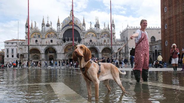 People walk on a catwalk at the flooded St.  Mark's Square during a period of seasonal high water in Venice, Italy, October 5, 2021. REUTERS/Manuel Silvestri