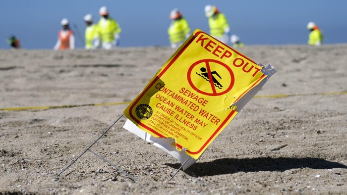 Aksi Bersih-bersih Pantai California dari Tumpahan Minyak A worker in protective suits cleans the contaminated beach after an oil spill in Huntington Beach, Calif., on Tuesday, Oct. 5, 2021. The Coast Guard received the first report of a possible oil spill off the Southern California coast more than 12 hours before a company reported a major leak in its pipeline and a cleanup effort was launched, records show. (AP Photo/Ringo H.W. Chiu)
