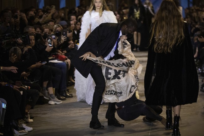 Aksi wanita tersebut tak berlangsung lama karena panitia dan tim sekuriti langsung mengamankannya. Ia sempat memberontak sehingga sampai terjatuh di catwalk. (Foto: Vianney Le Caer/Invision/AP)