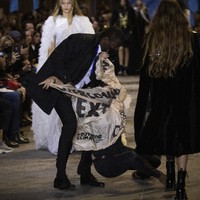 Aksi wanita tersebut tak berlangsung lama karena panitia dan tim sekuriti langsung mengamankannya. Ia sempat memberontak sehingga sampai terjatuh di catwalk. (Foto: Vianney Le Caer/Invision/AP)