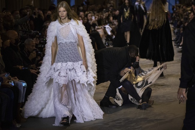 The show must go on. Meski terinterupsi, para model tetap berjalan memeragakan koleksi terbaru Louis Vuitton tersebut. (Foto: Vianney Le Caer/Invision/AP)