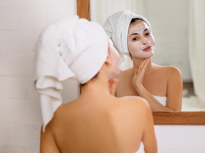 Beautiful woman having a facial cosmetic scrub treatment from professional dermatologist at wellness spa. Anti-aging, facial skin care and luxury lifestyle concept.