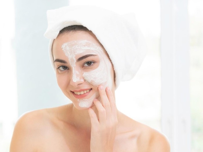 Beautiful woman having a facial cosmetic scrub treatment from professional dermatologist at wellness spa. Anti-aging, facial skin care and luxury lifestyle concept.