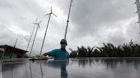 Warga membersihkan panel surya Pembangkit Listrik Tenaga Hybrid (PLTH) di Dusun Bondan, Desa Ujung Alang, Kampung Laut, Cilacap, Jateng, Rabu (6/10/2021). PLTH meupakan campuran tenaga surya dan tenaga angin. (Idhad Zakaria/AntaraFoto).