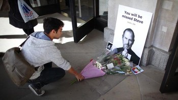 Seorang pengunjung di Apple Store Inggris menaruh karangan bunga sebagai penghormatan terakhir bagi Steve Jobs. Foto: Getty Images
