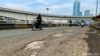 Sejumlah pengendara motor memperlambat laju kendaraannya karena permukaan aspal sedang dikelupas.