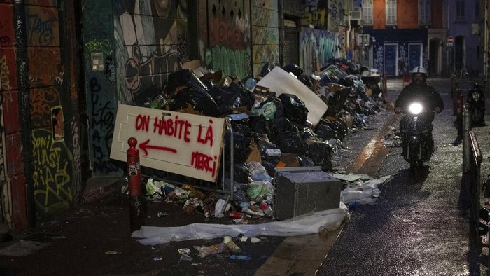 A pedestrian walks past a pile of burnt trash after an eight-day-long garbage collectors strike in Marseille, southern France, Wednesday, Oct. 6, 2021. (AP Photo/Daniel Cole)