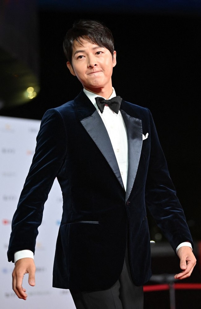 Song Joong Ki datang berbarengan dengan rekannya host Busan International Film Festival 2021, Park So Dam. Namun dia berpose di karpet merah sendirian dan tampil menawan dalam setelan jas hitam serta dasi kupu-kupu. Foto: AFP/JUNG YEON-JE