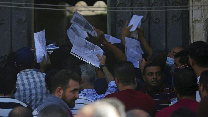 Palestinians hold their documents to apply for permits to work inside Israel in front of the chambers of commerce in Jebaliya, Northern Gaza Strip, Thursday, Oct. 7, 2021. Tens of thousands of Palestinians lined up outside chambers of commerce across the Gaza Strip on Wednesday, hoping to get permits to work inside Israel after rumors circulated that more would be issued to residents of the Hamas-ruled territory. (AP Photo/Adel Hana)