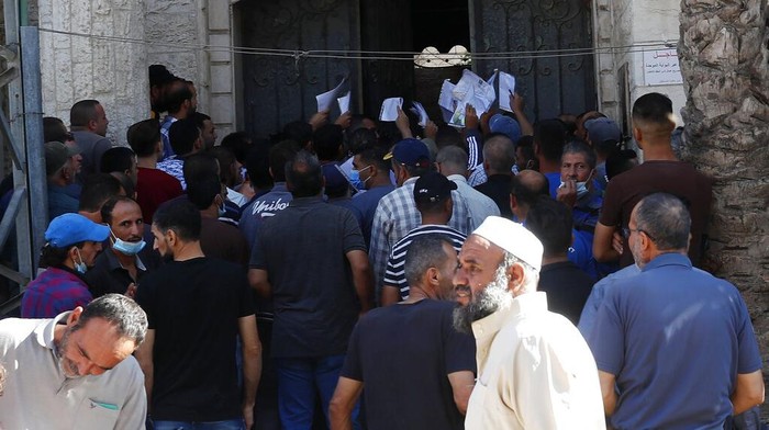 Warga Palestina Berebut Izin Kerja di Wilayah Israel Palestinians hold their documents to apply for permits to work inside Israel in front of the chambers of commerce in Jebaliya, Northern Gaza Strip, Thursday, Oct. 7, 2021. Tens of thousands of Palestinians lined up outside chambers of commerce across the Gaza Strip on Wednesday, hoping to get permits to work inside Israel after rumors circulated that more would be issued to residents of the Hamas-ruled territory. (AP Photo/Adel Hana)