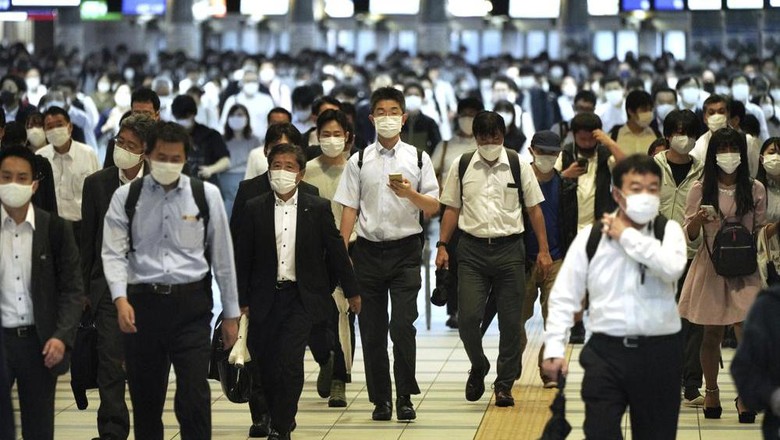 Commuters wearing face masks walk in a passageway during a rush hour at Shinagawa Station Friday, Oct. 1, 2021, in Tokyo. Japan lifted its COVID-19 state of emergency in all of the regions on Oct.1. (AP Photo/Eugene Hoshiko)