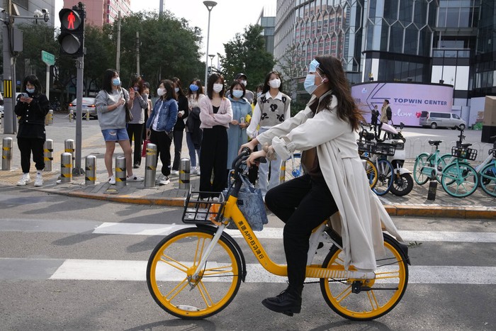 Pemandangan tak biasa terlihat di jalanan Beijing, China. Seorang warga mengenakan masker sampai dua sekaligus saat beraktivitas di luar rumah. Ini fotonya.