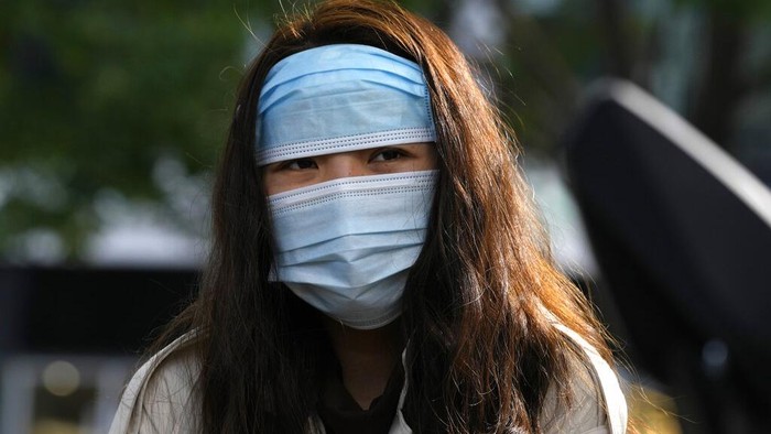 Pemandangan tak biasa terlihat di jalanan Beijing, China. Seorang warga mengenakan masker sampai dua sekaligus saat beraktivitas di luar rumah. Ini fotonya.