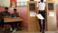 Seorang polisi lalu lintas membawa kertas suara usai mencoblos dalam pemilu parlemen di Kota Baghdad, Irak (8/10).  Sedikitnya 3.449 caleg berebut 329 kursi parlemen. (AP Photo/Hadi Mizban)