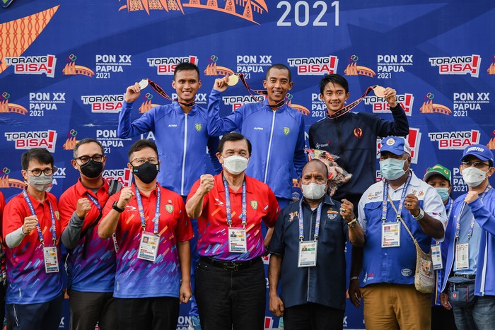 Menko Kemaritiman sekaligus Ketua Umum PB PASI Luhut Binsar Pandjaitan (tengah-bawah) bersama Menteri Kesehatan Budi G Sadikin (ketiga kiri) dan pejabat terkait berfoto bersama atlet peraih medali yaitu pelari Jawa Barat Agus Prayogo (tengah) bersama pelari Jawa Barat Pandu Sukarya (kiri) dan pelari Bangka Belitung Robi Sianturi pemenang pada nomor lari 5000 meter PON XX Papua di Stadion Atletik, Mimika Sport Complex, Selasa (5/10/2021). PB PON XX Papua / Rommy Pujianto