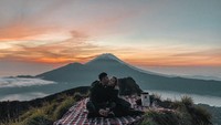 Jalan-jalan ke gunung Batur, Nikita Willy dan Indra Priawan asyik menyaksikan matahari terbit sambil minum minuman hangat. Keduanya juga sarapan sambil piknik di depan gunung ini.  Foto: Instagram @nikitawillyofficial94