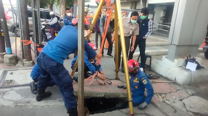 Petugas Damkar mengevakuasi kartu ATM yang jatuh ke Gorong-gorong Jakarta Timur.