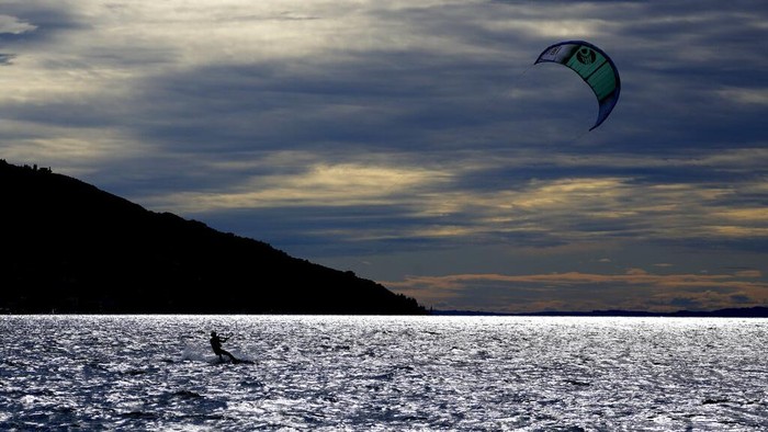 Surga Peselancar Angin di Danau Italia A kitesurfer surfs Lake Garda near Brenzone sul Garda, northern Italy, Saturday, Oct. 9, 2021. (AP Photo/Matthias Schrader)